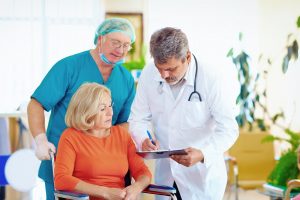 mature female patient on wheelchair listens to doctor perscripti